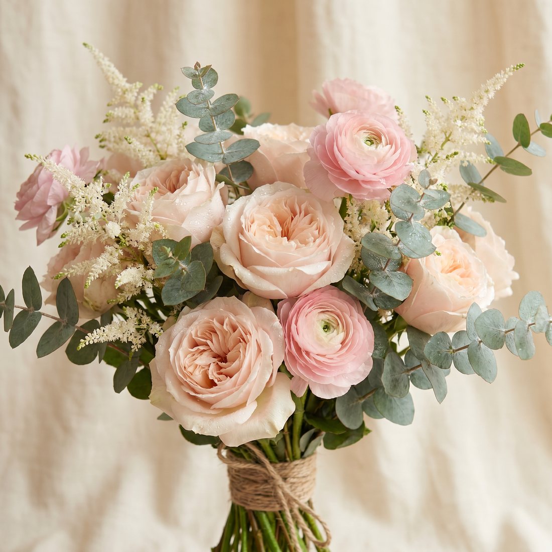 Weelderige bos blush rozen en ranonkels met astilbe, romantische bruidsstijl